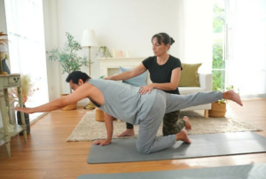 Instructora de yoga corrigiendo la postura de un alumno durante una clase de yoga a domicilio en Caracas